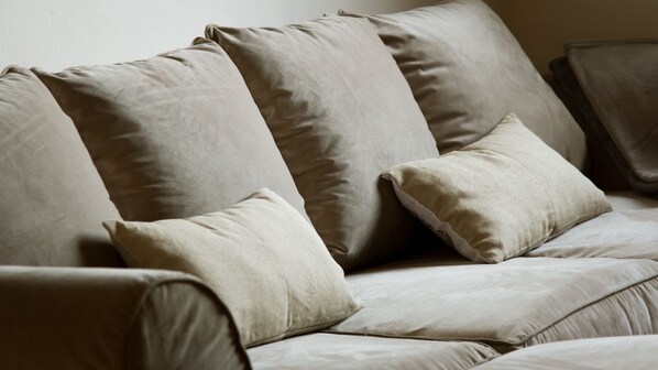 A beige sofa with multiple cushions.