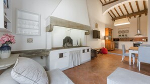 A spacious living area with a kitchen and dining area, featuring a rustic stone counter, white walls, and exposed wooden beams. - Welcome to G-HOUSE in FLORENCE  (Firenze)