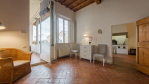 A room with a wicker chair, a white dresser, and a chair with a lamp. - Welcome to G-HOUSE in FLORENCE  (Firenze)