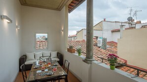 A balcony with a dining table set for breakfast, a sofa, and potted plants. - Welcome to G-HOUSE in FLORENCE  (Firenze)