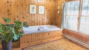 A wooden room with a bathtub, framed pictures on the wall, and a potted plant. - Rustic Romantic Bayberry Cottage at Autumn Ridge (Lexington)