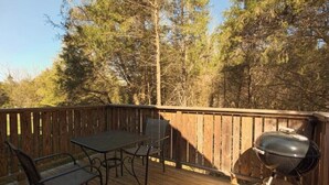 Una terraza de madera con mesa, sillas y una parrilla.