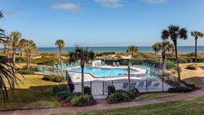 Uma área de piscina com várias espreguiçadeiras e vista para o oceano.