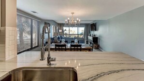 Uma cozinha moderna com bancada de mármore, uma torneira exclusiva e um espaço de jantar com sofá e mesa.