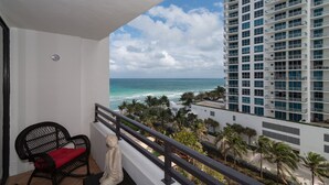 A balcony with a view of the ocean, a statue, and a chair. - On The Beach !!!  2 Minutes to Exquisite Dinning and Shopping (Hallendale Beach)