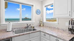 A kitchen with granite countertops, white cabinetry, a stainless steel sink, and two windows offering ocean views. - Stunning Oceanfront Property!  Newly Remodeled home with Incredible VIEWS (Crescent City)