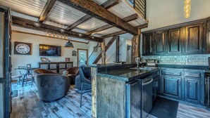 Une cuisine spacieuse avec des meubles de cuisine en bois foncé, un grand îlot central et un plafond au style rustique.