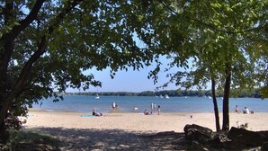 Ein Strand mit Menschen, Booten und Bäumen.
