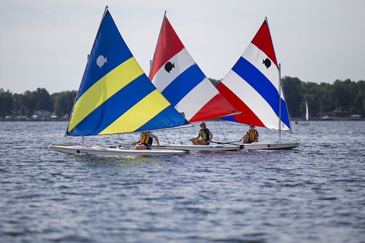 Twee zeilboten met kleurrijke zeilen op een rustig wateroppervlak.