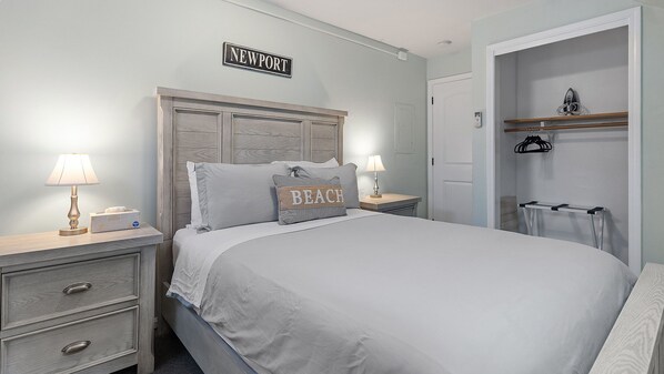 Une chambre à coucher bien rangée, avec un lit, des tables de chevet, une commode, une coiffeuse et une armoire.