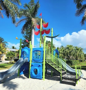 A playground with slides, climbing structures, and a flag.
