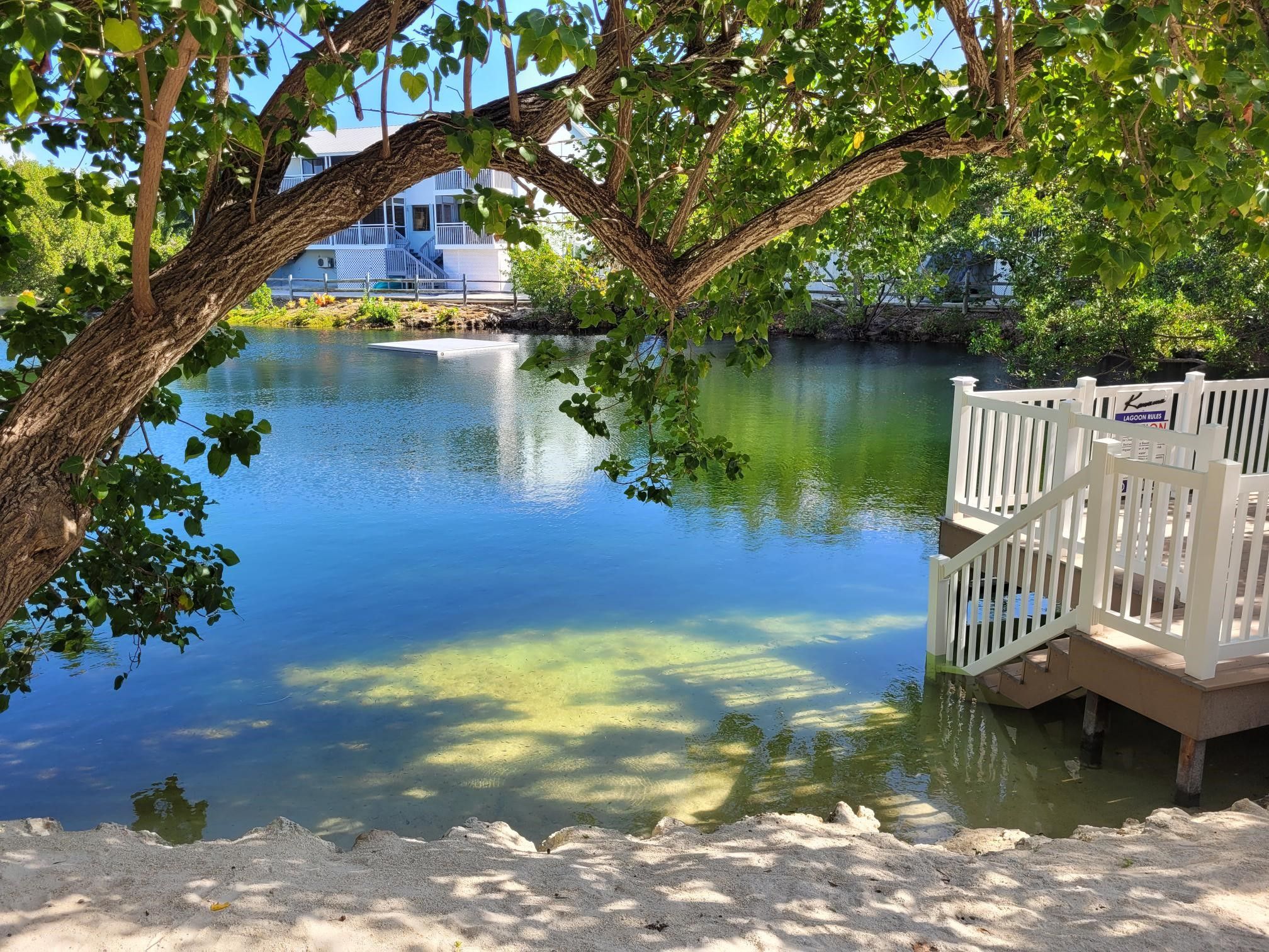 A serene lake with a dock and a white fence.