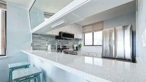 Une cuisine moderne dotée d’un grand îlot central, d’appareils électroménagers en acier inoxydable et offrant une vue sur la ville.