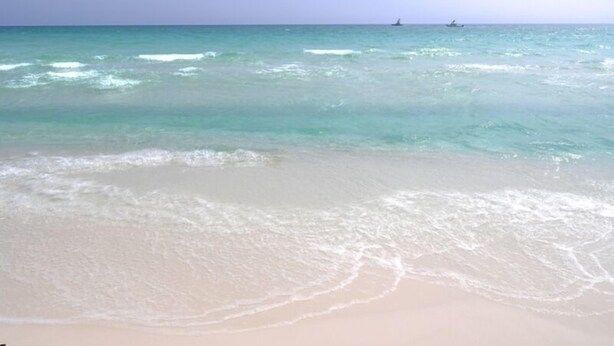 Une plage à l’eau turquoise et limpide, où les vagues sont douces.