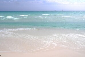 Ein Strand mit klarem türkisblauem Wasser und sanften Wellen.