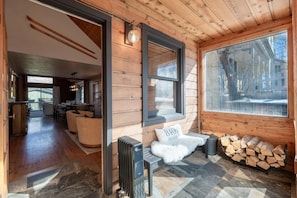 L’intérieur chaleureux d’un chalet comprend un coin repas, une cheminée et une grande fenêtre donnant sur l’extérieur.