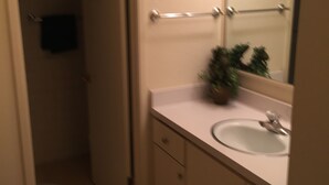 Un baño con lavabo, espejo y perchero para toallas.