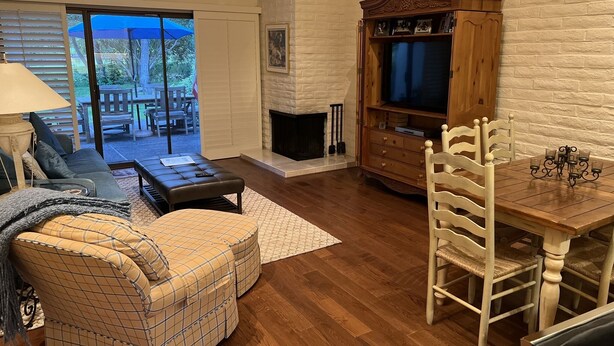 Una sala de estar con chimenea, un sofá, una mesa de comedor con sillas y un mueble para la televisión.