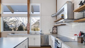 A modern kitchen with white cabinets, a stainless steel dishwasher, and a large window offering a mountain view. - 5-Star Lodge \ Groups Welcome  \ 1 Mile from Downtown (Leavenworth)