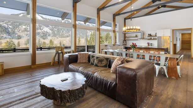 A spacious living area with a wooden floor, a leather sofa, and a dining table with chairs. - 5-Star Lodge \ Groups Welcome  \ 1 Mile from Downtown (Leavenworth)