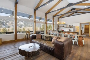 Un espacio habitable amplio con piso de madera, un sofá de cuero y una mesa de comedor con sillas.
