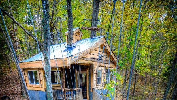Un puente colgante de madera que lleva a una cabaña en un bosque.