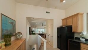 A kitchen with wooden cabinets, a black refrigerator, and a dining area with a ceiling fan. - Lake front getaway! Casita d’Amore (Granite Bay)