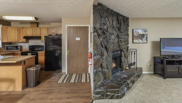 Eine moderne Küche mit Holzausstattung, einem schwarzen Kühlschrank, einer Mikrowelle und einem Herd.