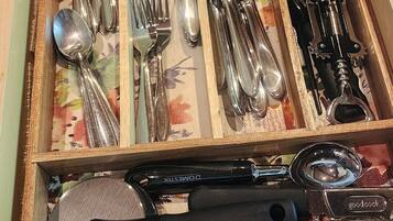 A drawer with various kitchen utensils including spoons, forks, knives, and a can opener.