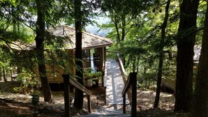 A wooden cabin with a deck, surrounded by trees. - Couples Retreat with Hot Tub, Lake & Mountain Views in Big Canoe Luxury Resort (Jasper)