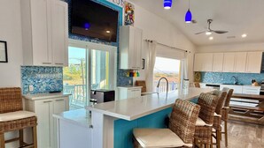 Una cocina moderna con una isla central, armarios blancos y salpicadero azul.