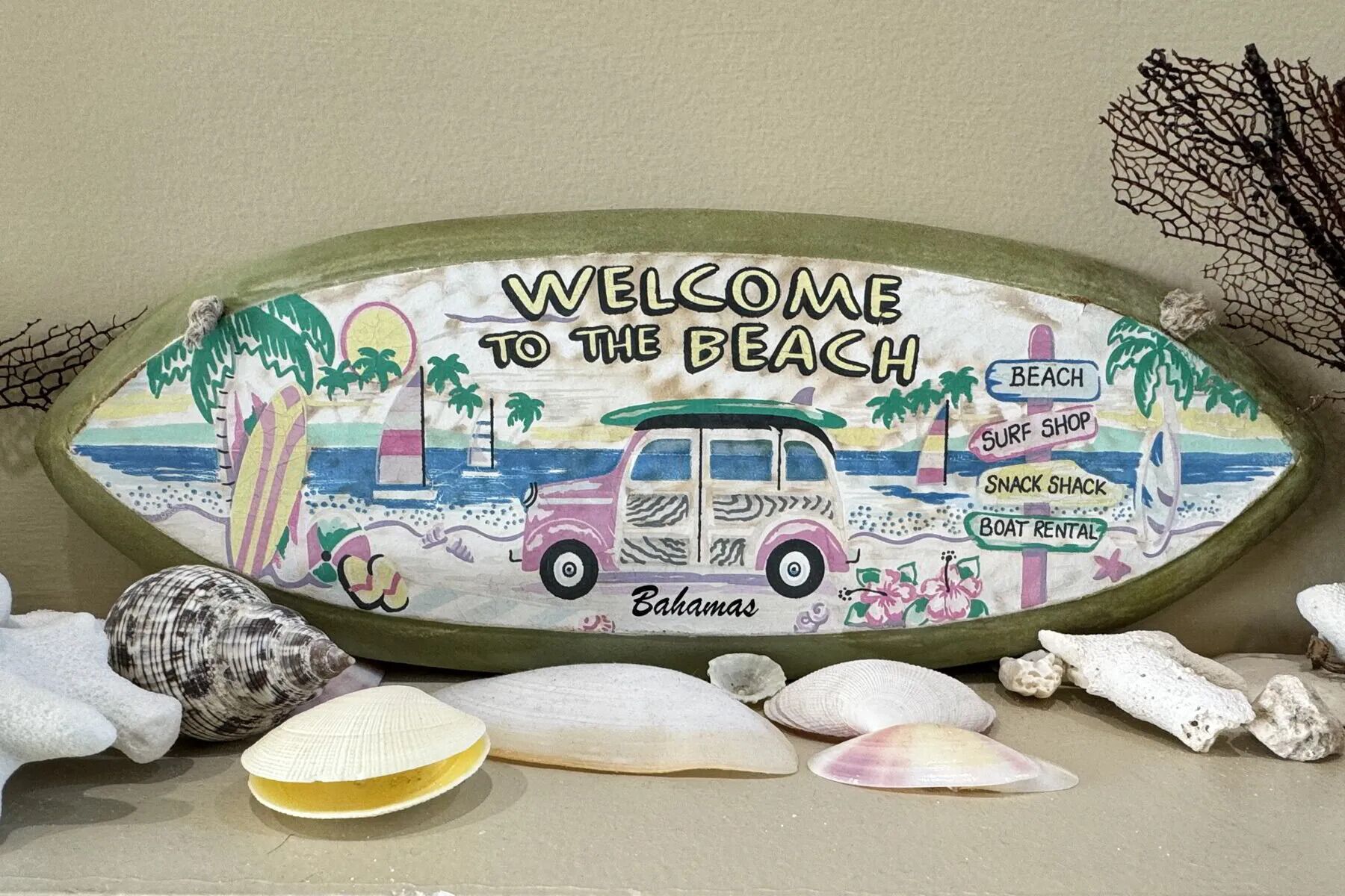 A beach-themed welcome sign with amenities like a beach, surf shop, snack shack, and boat rental.