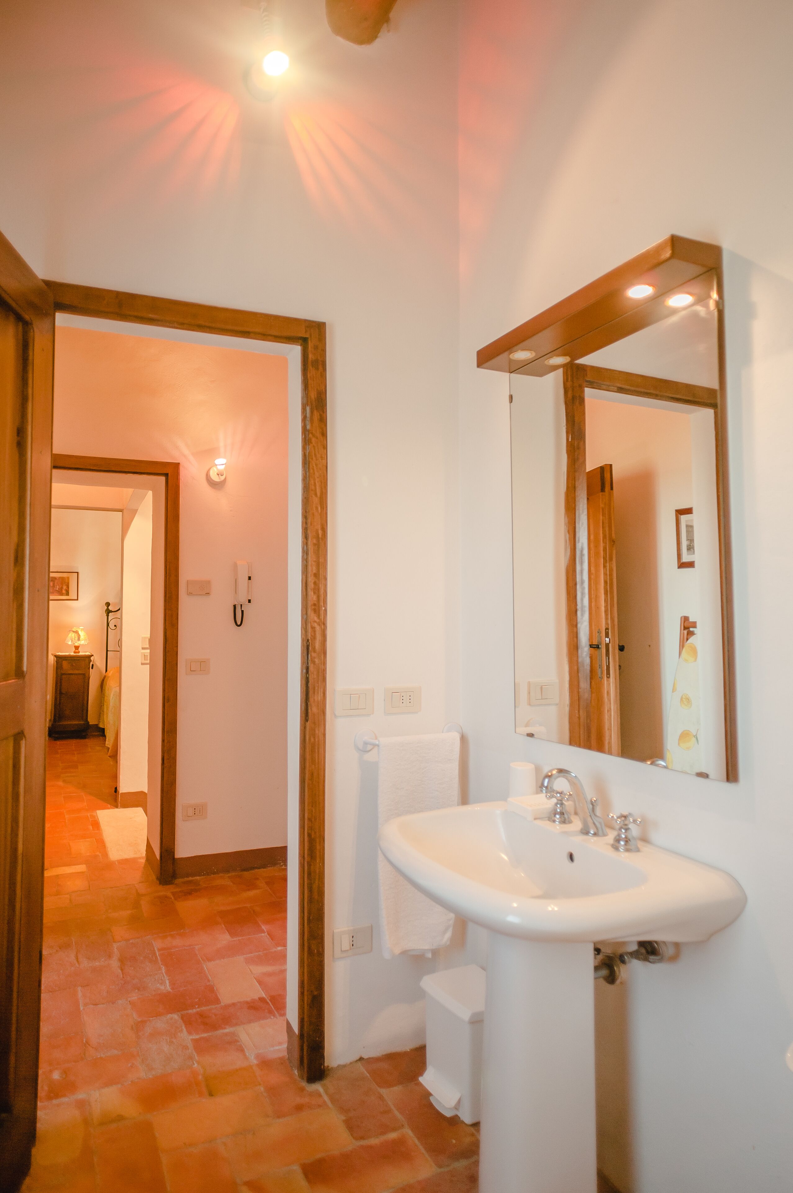 A bathroom with a white sink, a mirror, and a shower visible through an open door.