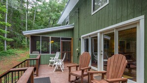 A wooden deck with two Adirondack chairs and a covered area with a window. - Awesome Lakefront House on West Point Lake in LaGrange, Ga (Lagrange)
