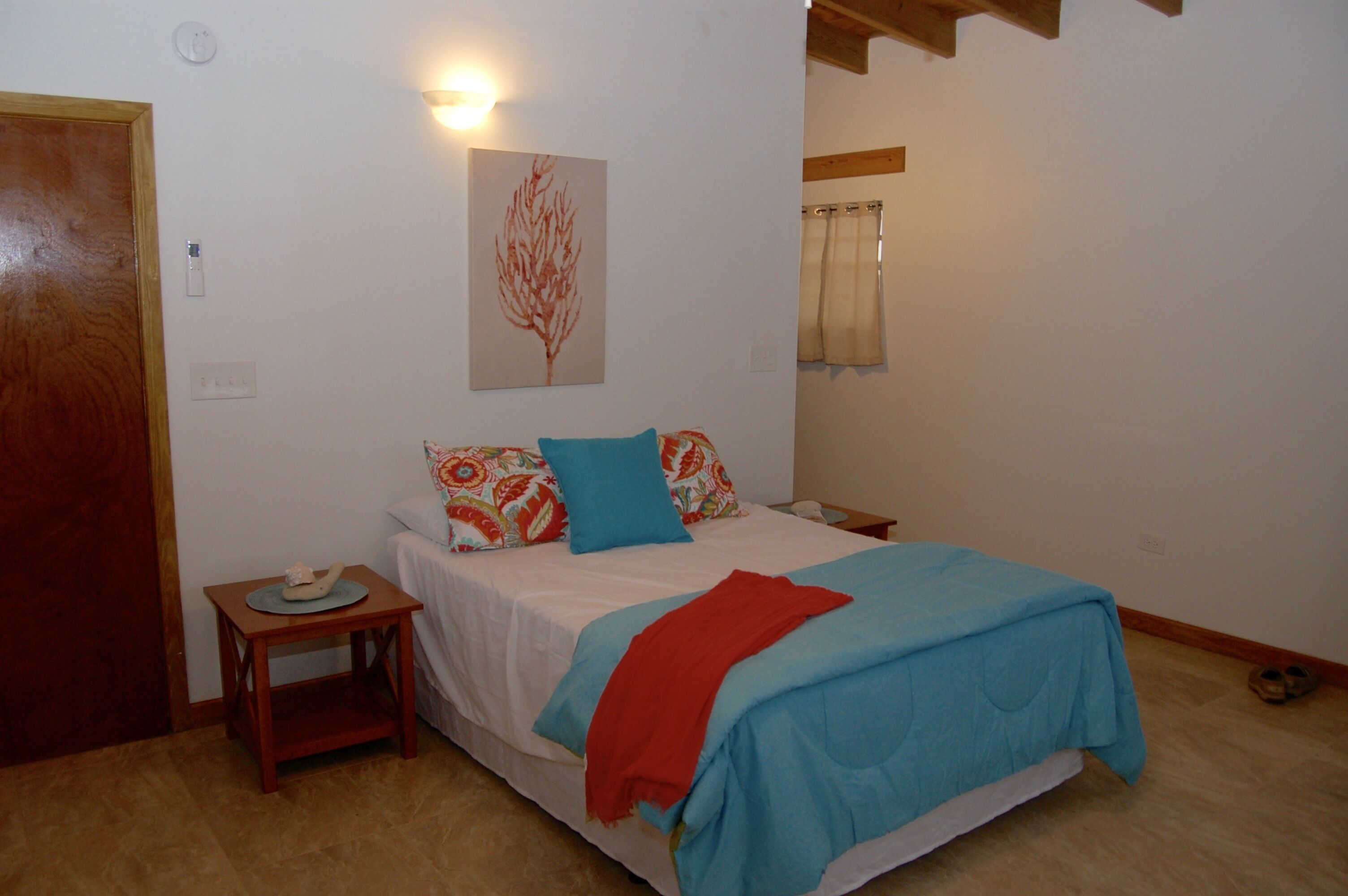 Un dormitorio con una cama, una mesita de noche, una lámpara de pared y una puerta.