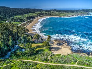 A coastal landscape with a beach, forested hills, and a clear sky. -  Charming Beach Front Cottage  (Carmel)