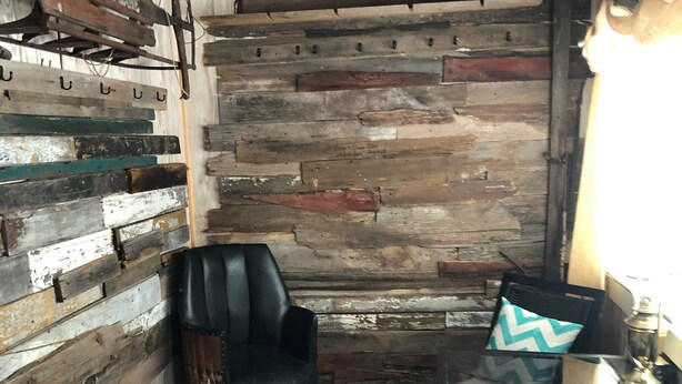 A rustic interior with a wooden wall, a leather chair, a table with a lamp, and a patterned cushion. - Family Friendly, Located Between Two Ski Hills, cable tv, WiFi, Off Road Parking (Laurium)