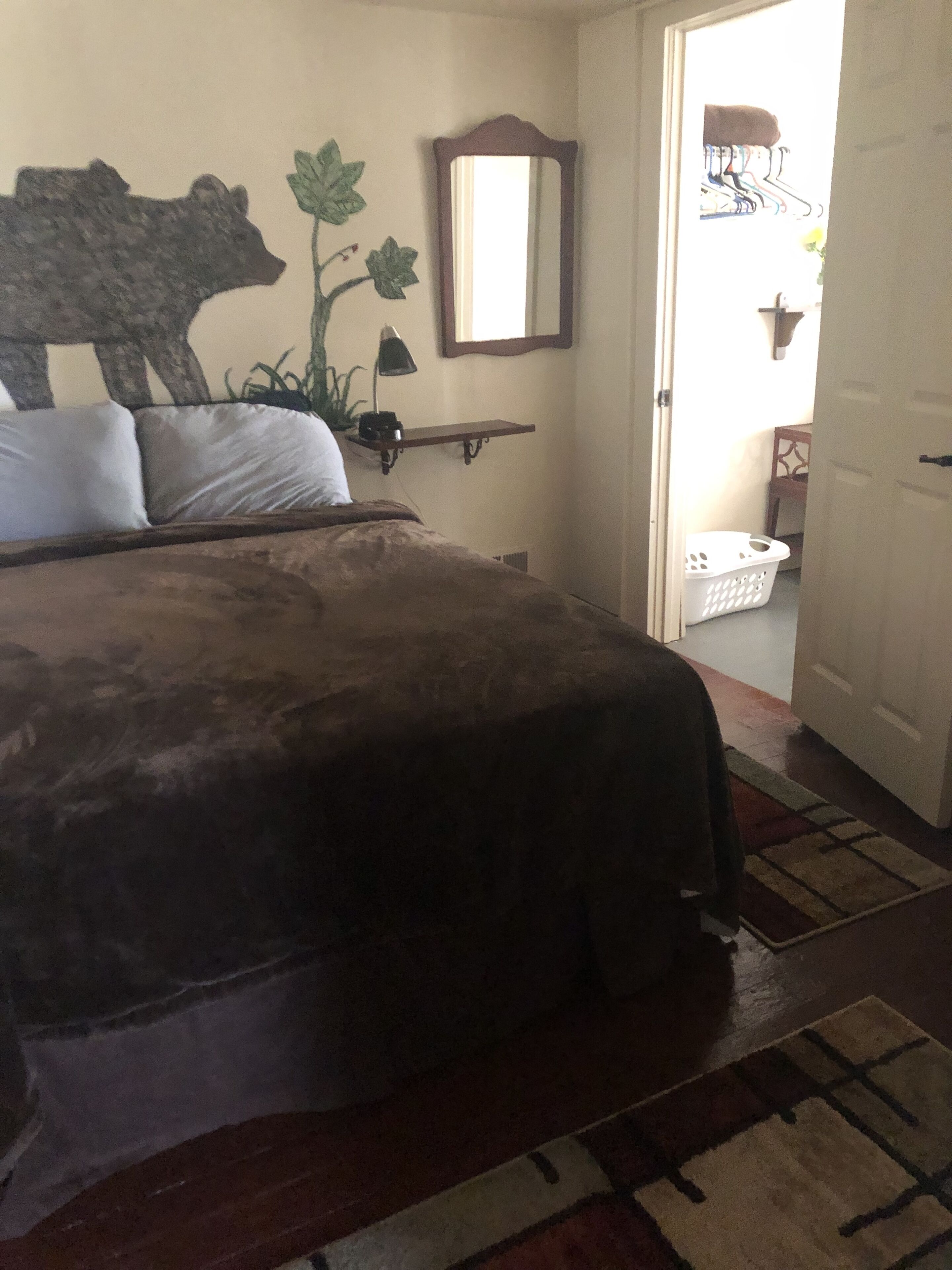 A bedroom with a bed, a mirror, a shelf, and a door leading to a balcony.
