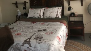A bedroom with a bed, wooden headboard, two nightstands, a ceiling fan, and a wall-mounted fan. - Family Friendly, Located Between Two Ski Hills, cable tv, WiFi, Off Road Parking (Laurium)