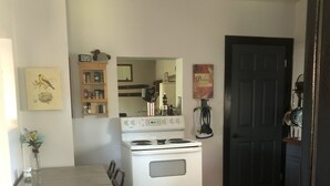 A compact kitchen with a white stove, wooden floor, and a dining area with a chair. - Family Friendly, Located Between Two Ski Hills, cable tv, WiFi, Off Road Parking (Laurium)