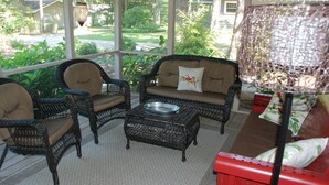 A covered porch with wicker furniture, a metal bowl, and a red bench. - Beautiful Private Harbert Beach cottage well appointed on a quiet private lane (Harbert)