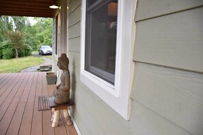 Una estatua sobre una cubierta de madera, una ventana y un vehículo al fondo.