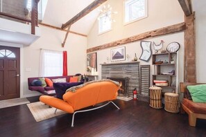 Un amplio salón con chimenea, un sofá, un banco de madera y una estantería.
