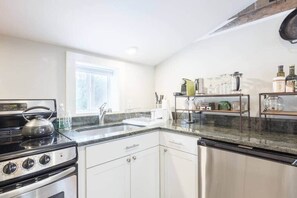 Una cocina moderna con estufa, pileta y lavavajillas integrado.