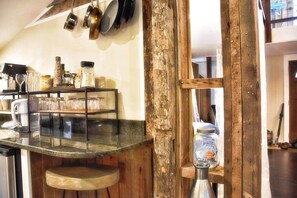 A kitchen with a wooden bar counter, hanging pots, and a rustic wooden door.