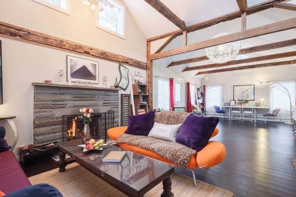 A living room with a fireplace, a sofa, a coffee table, and a dining area in the background.