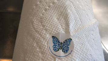 Superficie blanca texturizada con un adhesivo circular que muestra un diseño de mariposa azul y texto.