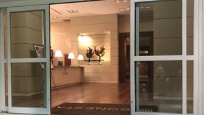 A hotel lobby with a reception desk, three lamps, and a decorative sculpture.