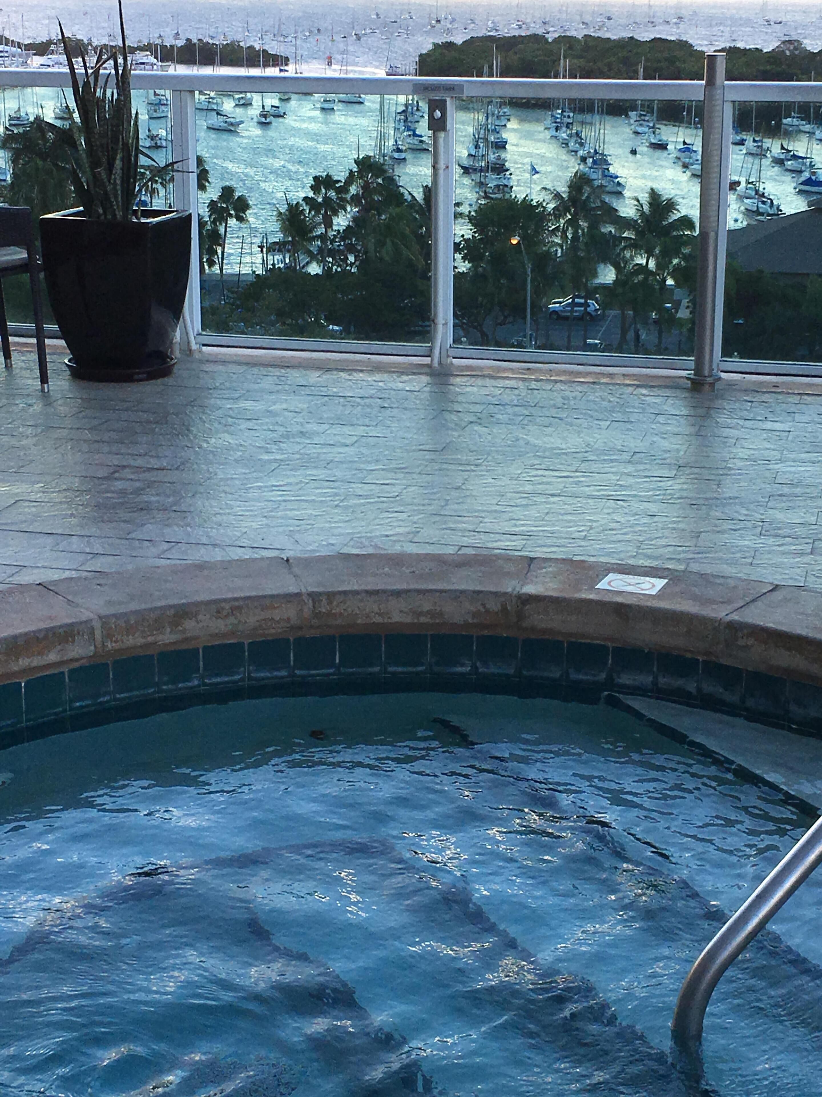 A pool area with a view of a marina and boats.