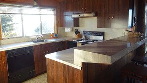 A kitchen with wooden cabinets, a stainless steel stove, and a large island with a sink. - Heart Stopping Ocean Views, Secluded Getaway, Whale Watching (Little River)